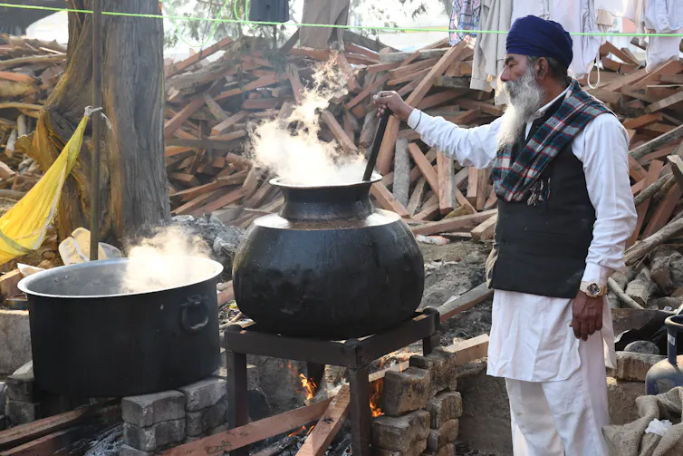 A Sikh man stirs pots at a farmers' protest camp on the New Delhi border, December 2020.