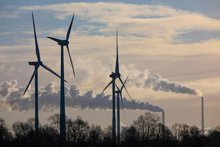 Wind turbines with industrial chimney in background