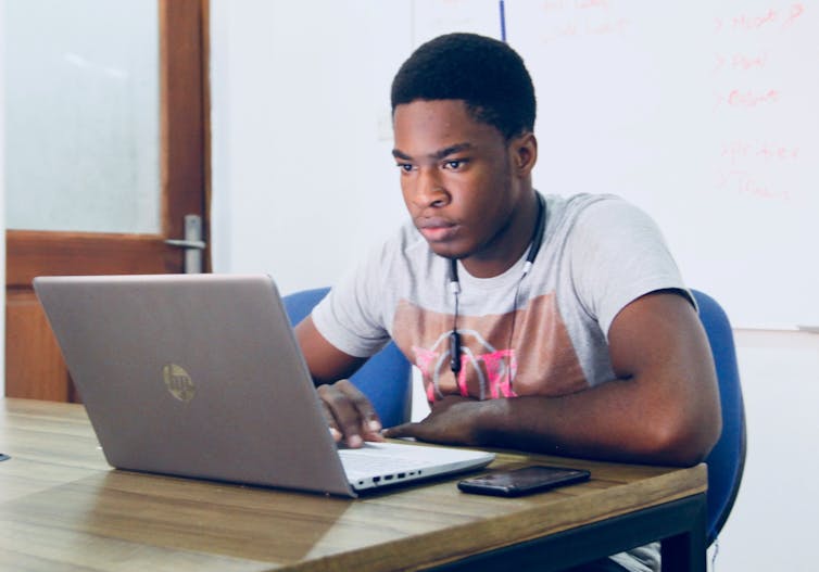 A man intently looks at his laptop.