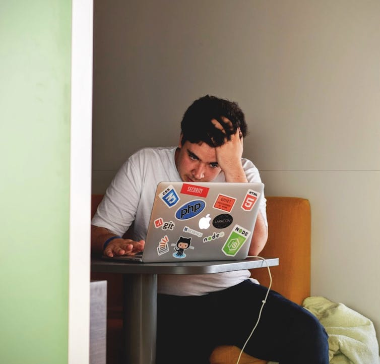 Un uomo si passa una mano tra i capelli e sembra agitato davanti al suo laptop