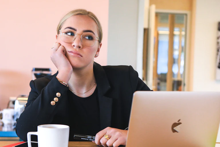 A woman sits at her laptop looking upset.