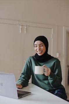 A woman smiles at her laptop.