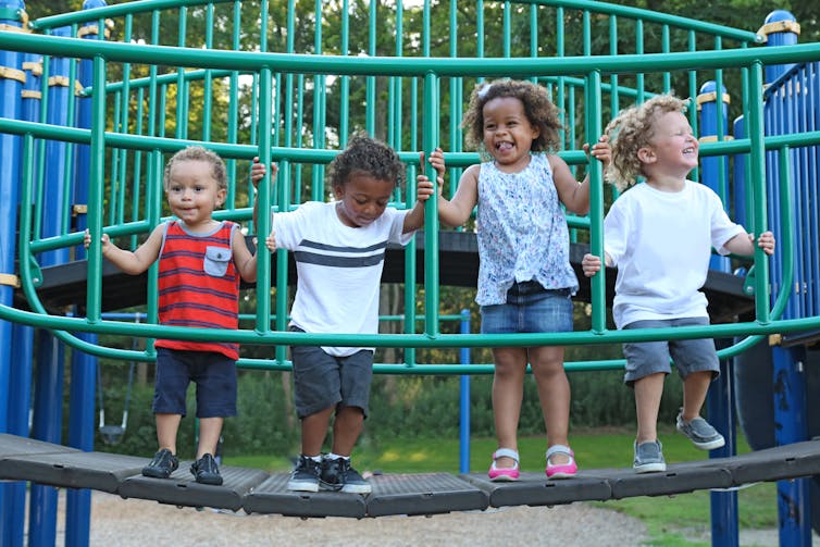 Children standing on playground bridge.