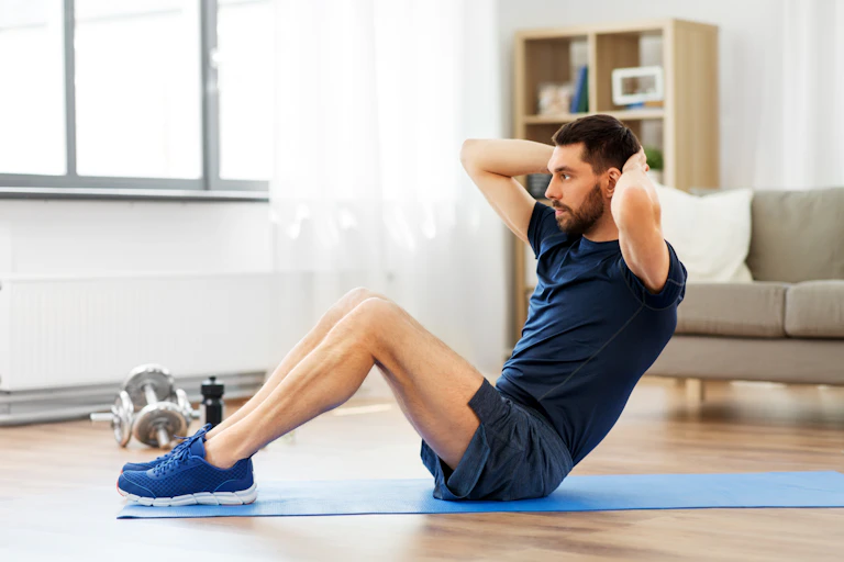 A young man does a sit-up at home.