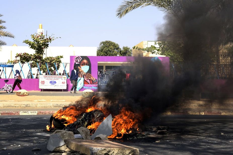 A fire burns in the middle of a road following protests in Dakar