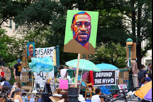 Protest signs against police brutality with signs showing portraits of George Floyd's face