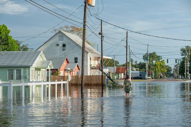 Two people walk through a flooded street.