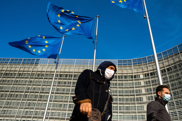 Two people walk in front of the EU headquarters in Brussels.