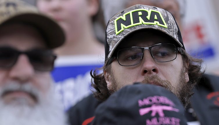 A man in a cap with the NRA logo looks askance.