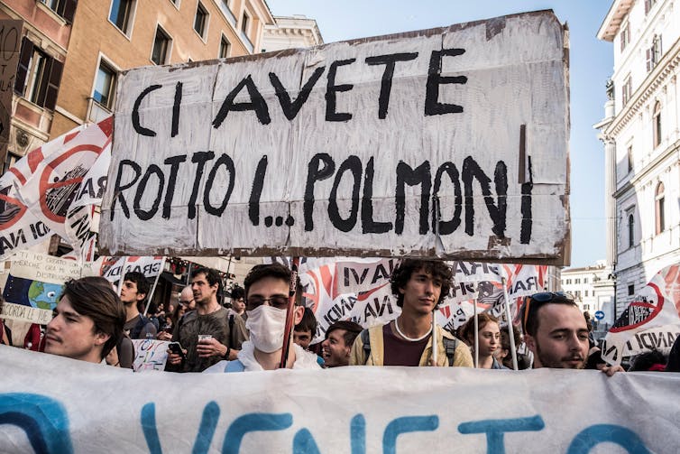 Protesters hold sign saying 'ci avate rotto i polmoni'