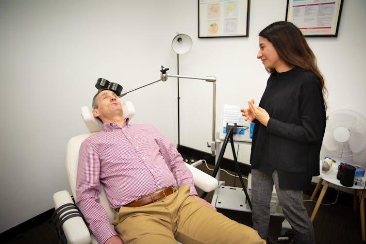 Man receiving treatment, lying down with magnetic coil on head