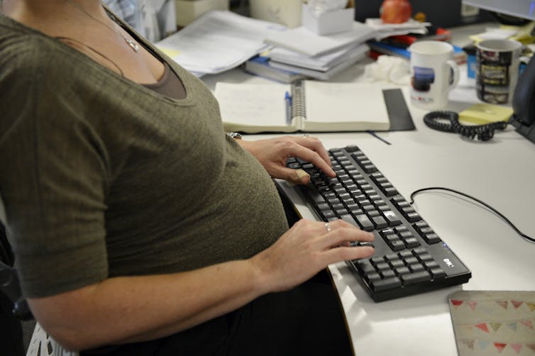 Pregnant woman sitting at her desk.