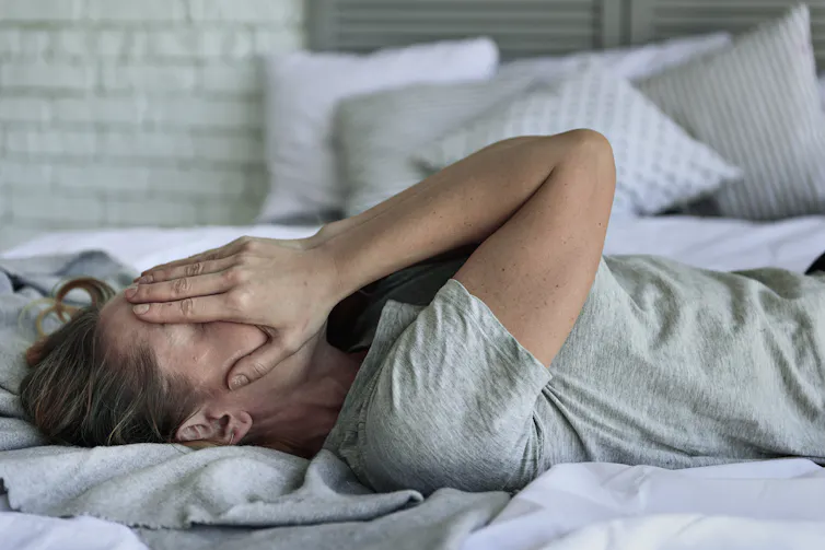 A woman with fatigue from long COVID lying on a bed
