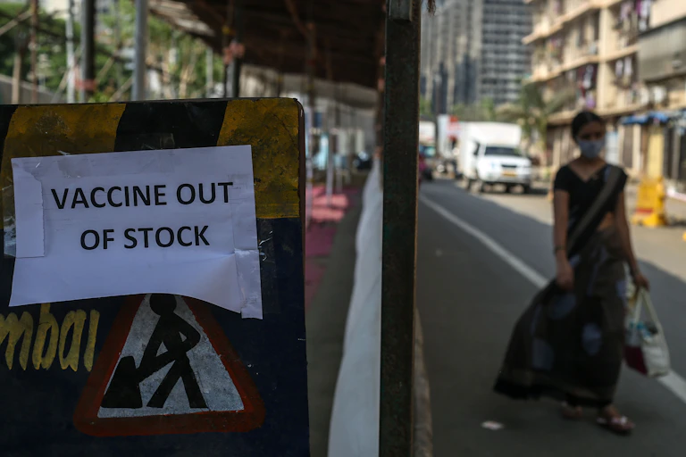 Sign saying 'vaccine out of stock' as woman walks past.