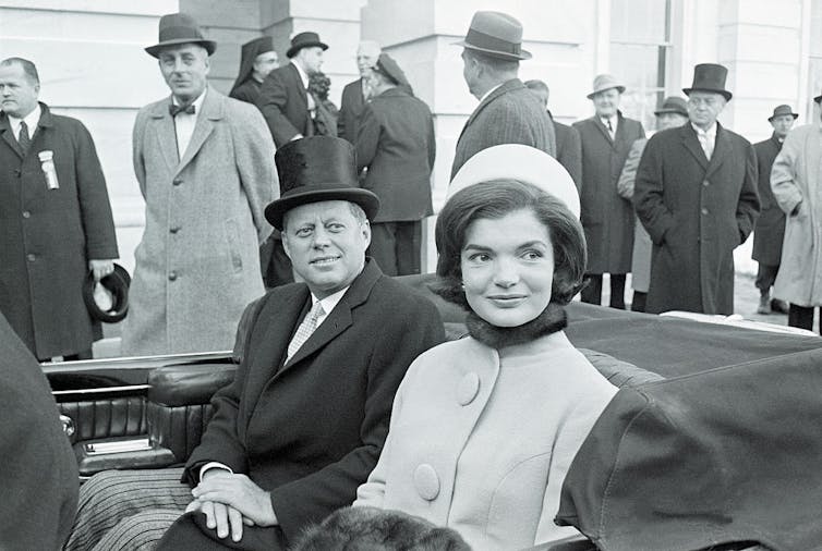 Jackie Kennedy rides in a car alongside John F. Kennedy.