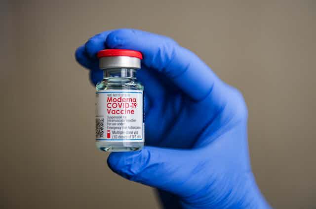 Person holding a vial of the Moderna COVID-19 vaccine