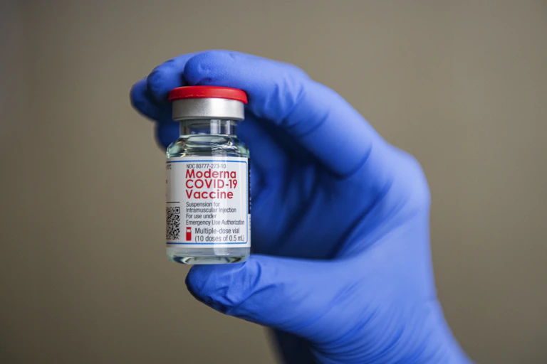 Person holding a vial of the Moderna COVID-19 vaccine