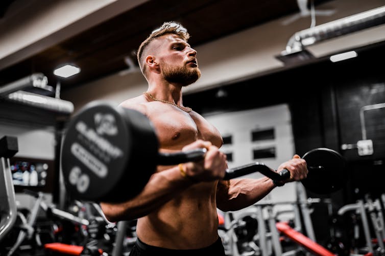 A young man lifts a weight in the gym.