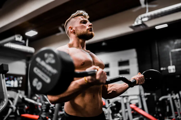 A young man lifts a weight in the gym.