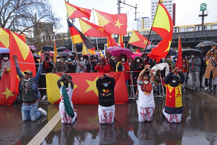 Protestors kneel in front of Tigrayan flags