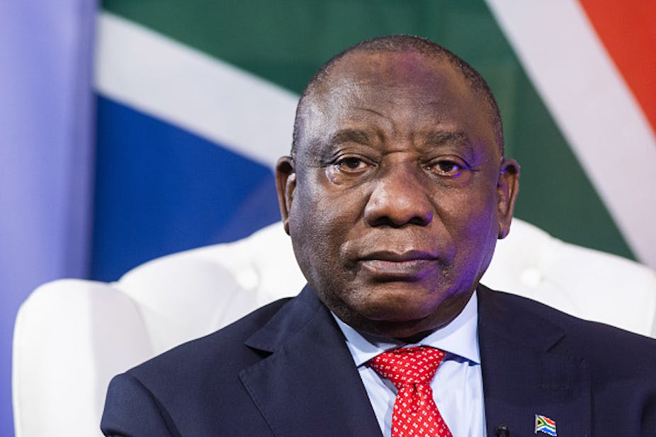 Head and shoulders of man facing the camera with the flag of South Africa behind him