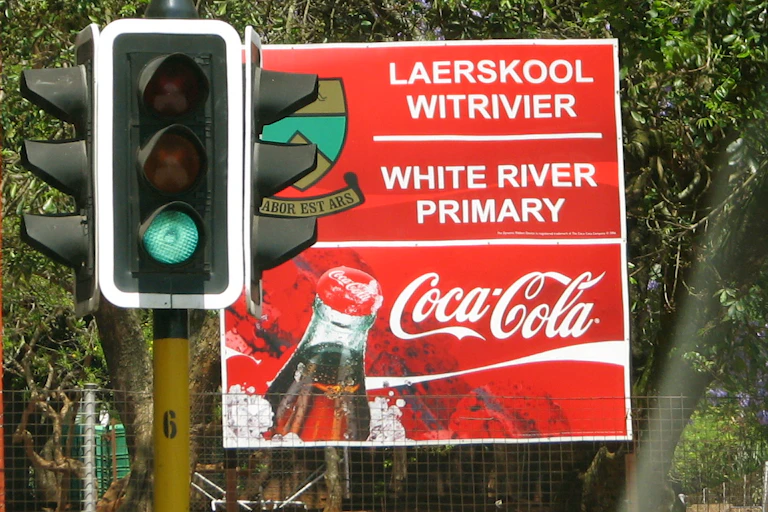 A sign at a school with sponsorship from Coca Cola.