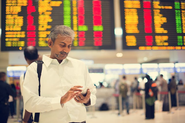 An Indian man checking his phone in an airport