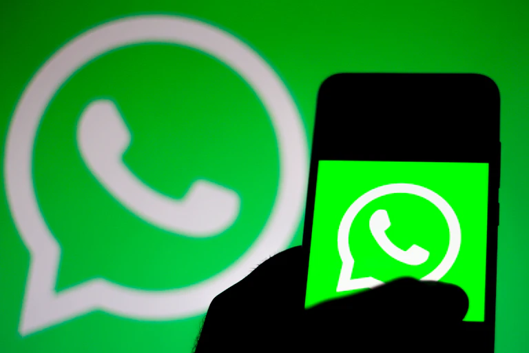 A phone showing the WhatsApp logo in front of another WhatsApp logo