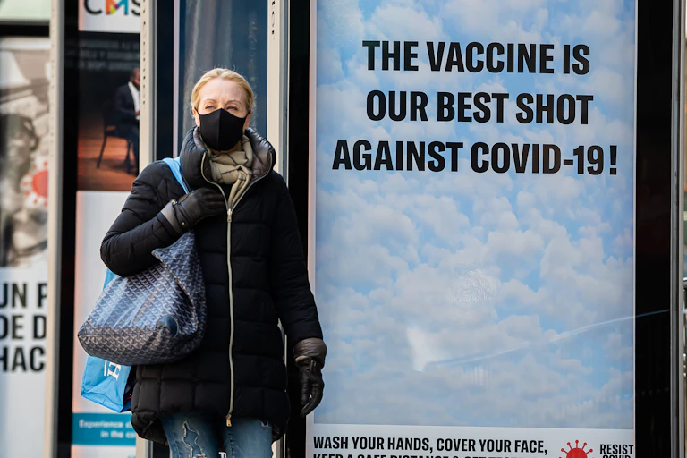 A woman walks past a sign saying that the vaccine is our best shot.