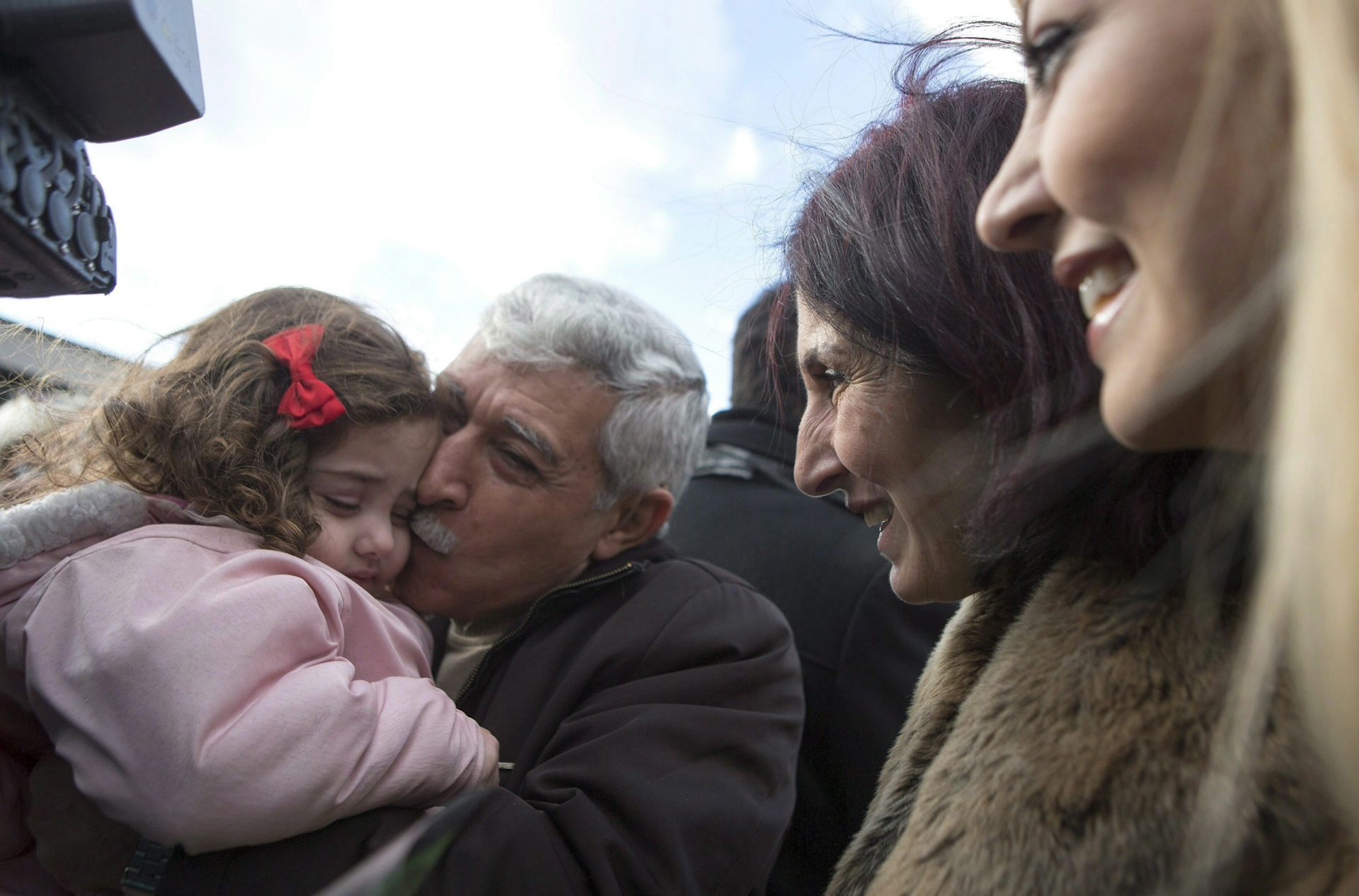 A Syrian-Canadian man hugs and kisses his newly arrived grand-daughter