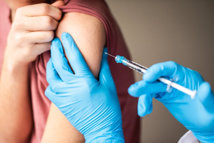 A needle with the COVID-19 vaccine is injected into the arm of a child.