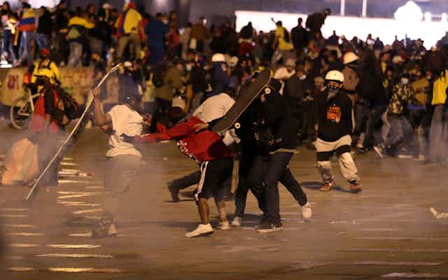 Des jeunes manifestants se protègent des gaz lacrymogènes en se servant de leur planche à roulettes comme bouclier.