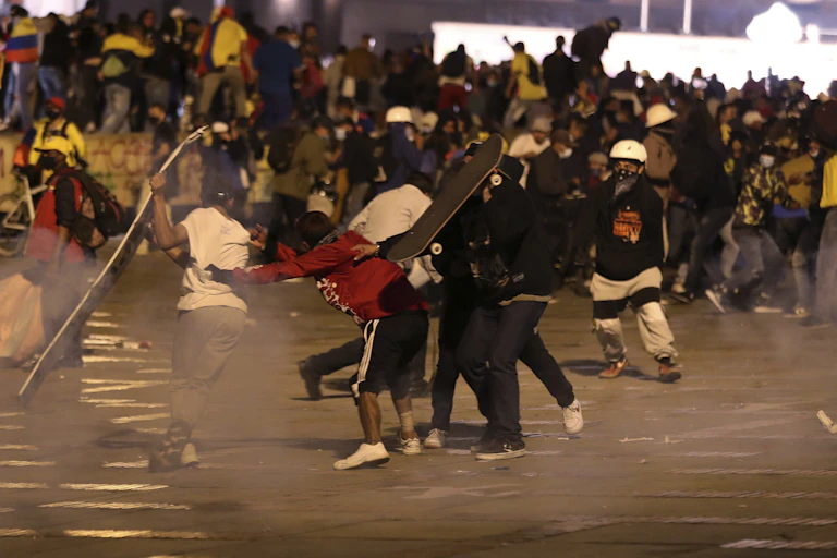 Des jeunes manifestants se protègent des gaz lacrymogènes en se servant de leur planche à roulettes comme bouclier.