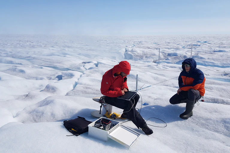 Scientists study equipment on an icy tundra