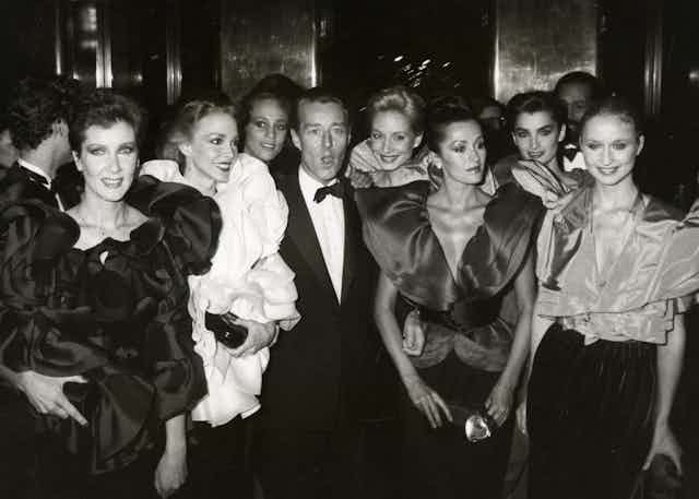 Halston poses with a group of elegantly dressed models.