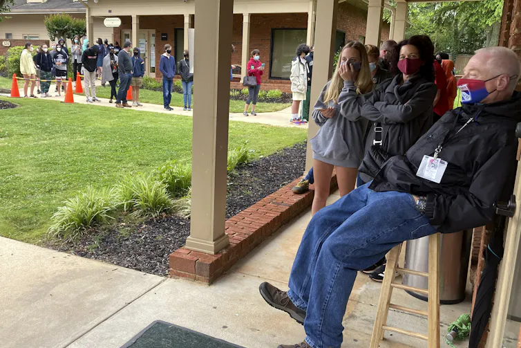 Young people waiting outdoors in a socially distanced lineup