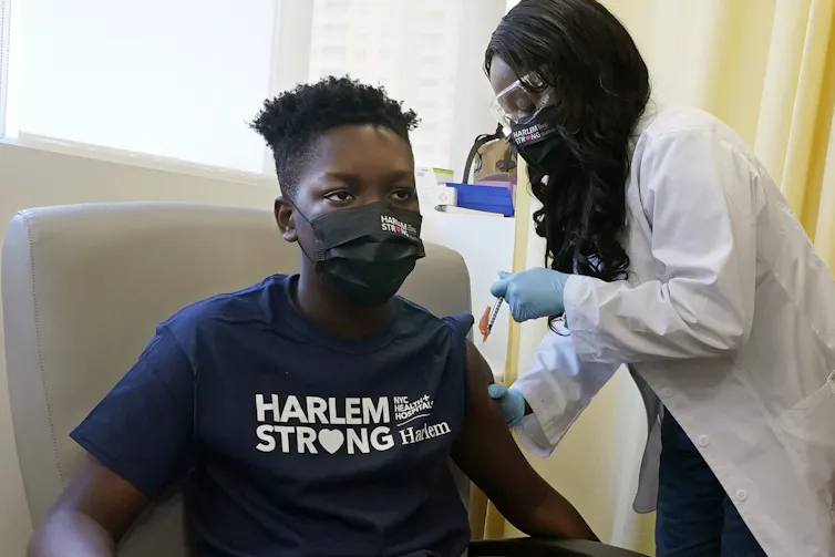 A child receiving an injection in his arm from a health-care worker