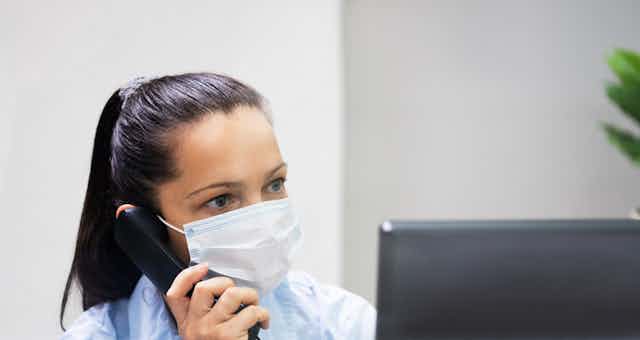 Receptionist wearing mask on phone at computer