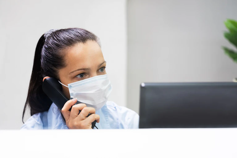 Receptionist wearing mask on phone at computer