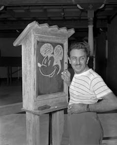Man draws cartoon mouse on chalkboard