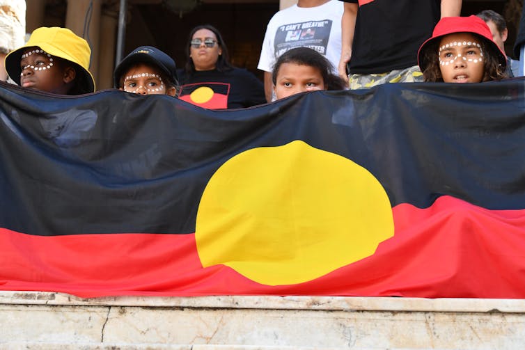 Children hold an Indigenous flag at a Black deaths in custody rally.