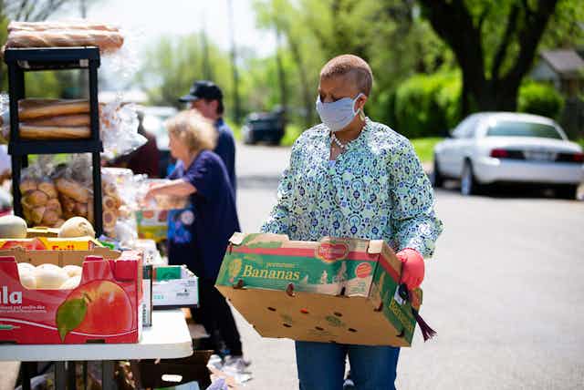 Volunteer carrying box of donated food across road