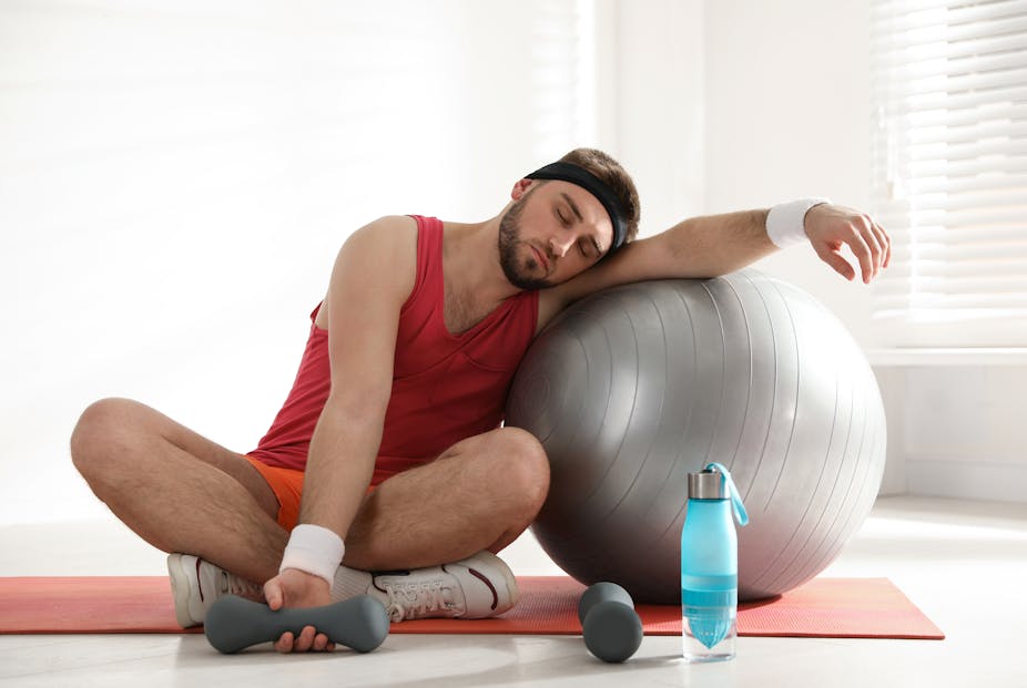 Lazy man resting his head on an exercise ball instead of doing his workout.