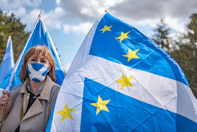 A woman waves a flag with EU stars superimposed on a Scottish saltire
