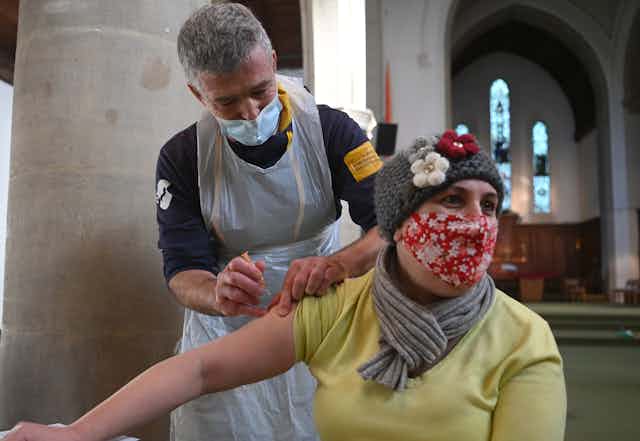 A woman in a face mask being vaccinated