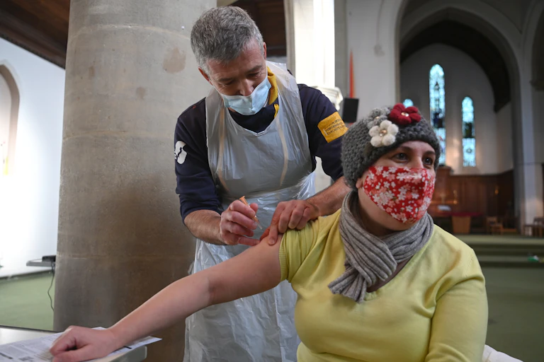 A woman in a face mask being vaccinated