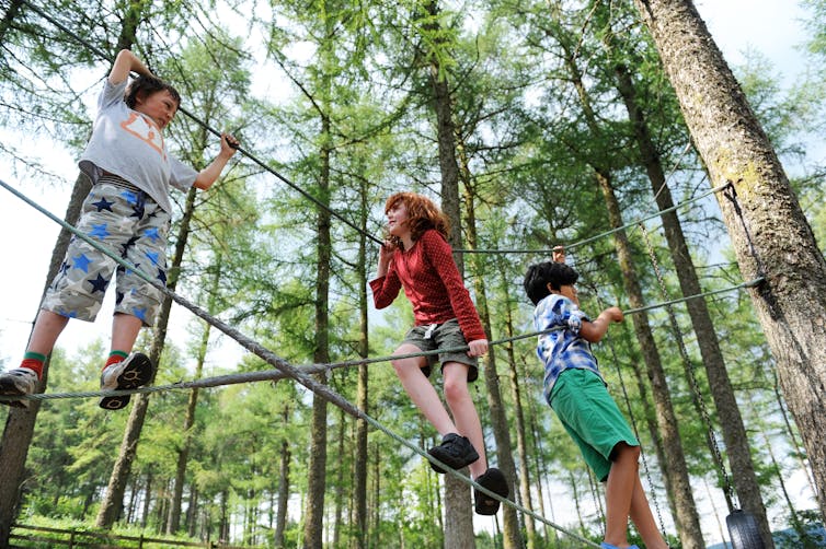 Children climb on a structure in a forest in Wales