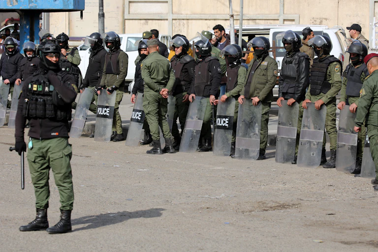 Iraqi police officers in protective clothing with helmets, shields and batons.