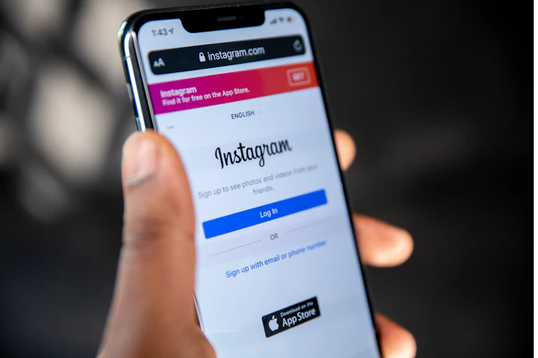 Hand holds a phone displaying the Instagram login page on browser