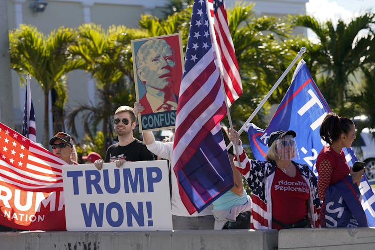Os apoiadores do Trump agitam bandeiras e seguram uma placa que diz Trump Won